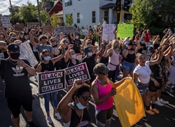 [ai] A large group of diverse protesters holding signs that read 'Black Lives Matter' while raising their fists in the air, gathered on a street during a demonstration for racial equality.